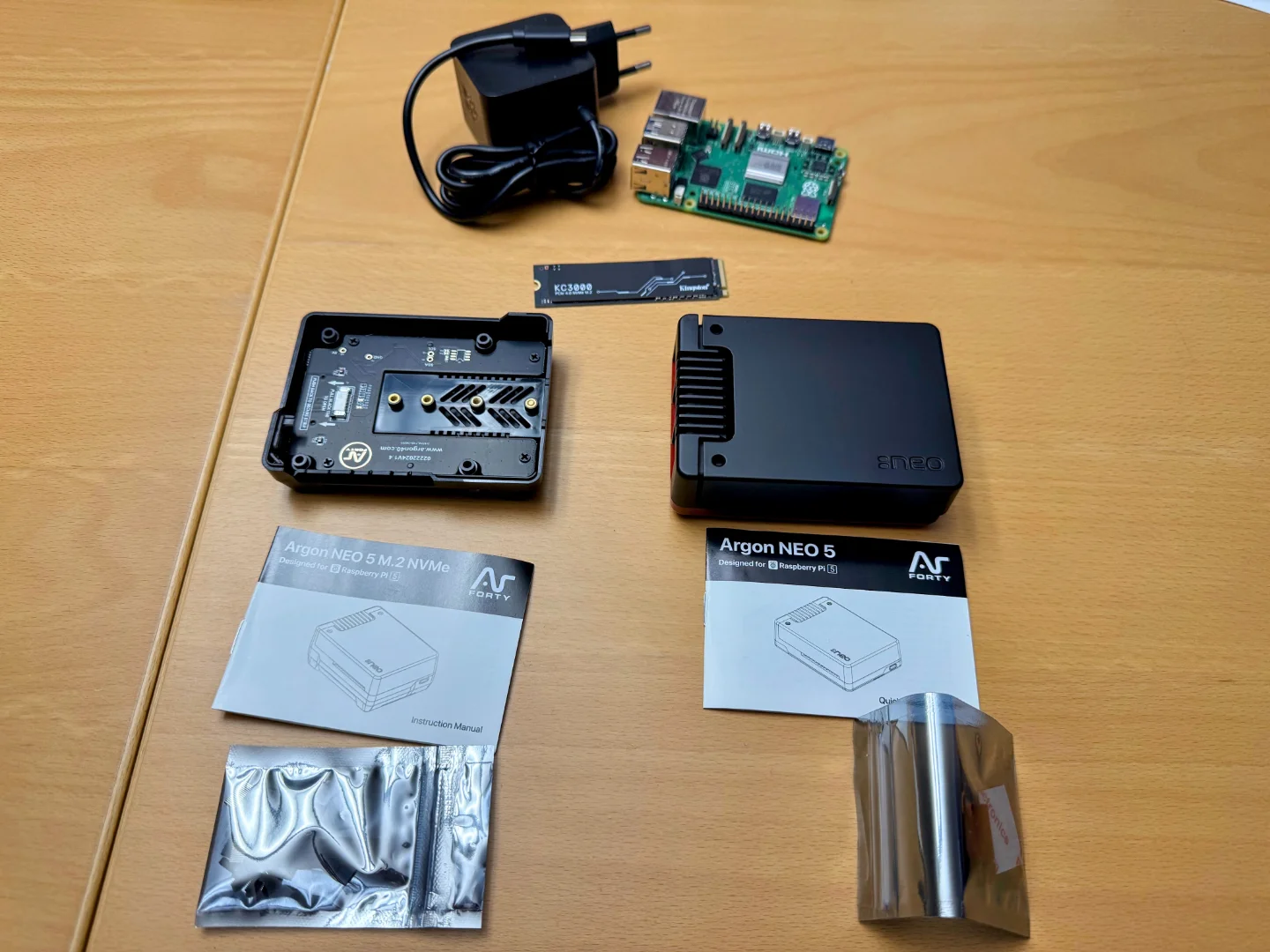 The components for my new Raspberry Pi 5 setup unboxed: Raspberry Pi 5, Argon NEO 5 case, and Kingston KC3000 NVMe disk. Unboxed.